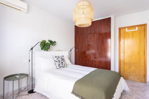 a bedroom with a white bed and a wooden door at Home2Book Stylish Apartment Caletillas in Candelaria