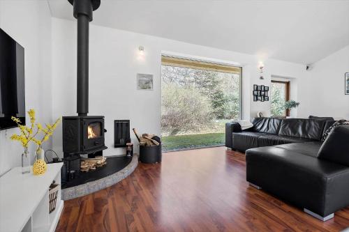 a living room with a black couch and a fireplace at Wellness Oase med Sauna, Fodbad og Højhastighed Internet i Naturens Fred og Ro in Nibe