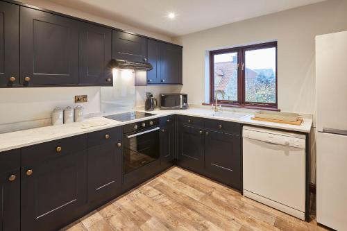a kitchen with black cabinets and white appliances at Host & Stay - The Fox in Scarborough