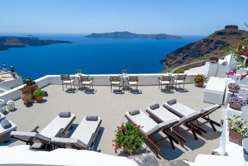 a patio with chairs and tables and a view of the ocean at Lithies Traditional Homes in Firostefani