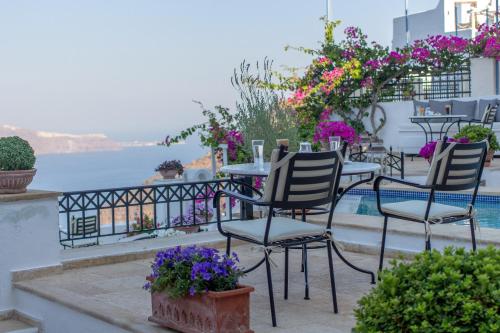 a table and chairs on a balcony with flowers at Lithies Traditional Homes in Firostefani