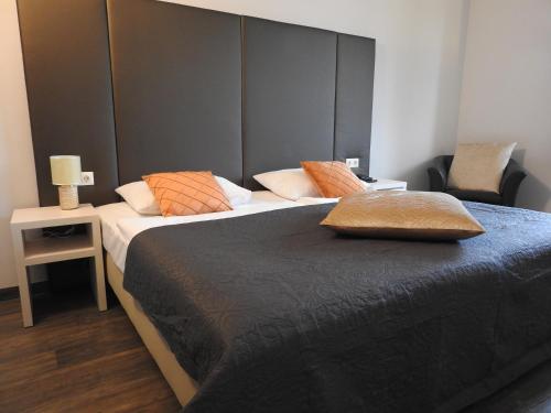 a bedroom with two beds with a headboard and a chair at Hotel Marc Aurel in Petronell