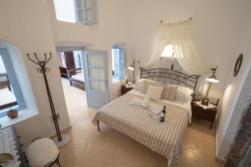 a bedroom with a large bed with white sheets and pillows at Lithies Traditional Homes in Firostefani