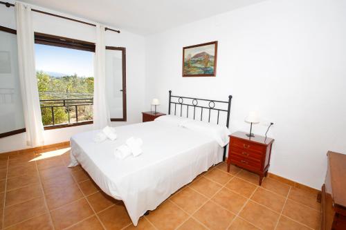 um quarto com uma cama branca e uma grande janela em Senia Tomaset II em Onil