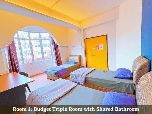 een kamer met 2 bedden, een tafel en een raam bij KSK Kasih Sayang Kluang Hometel in Kluang