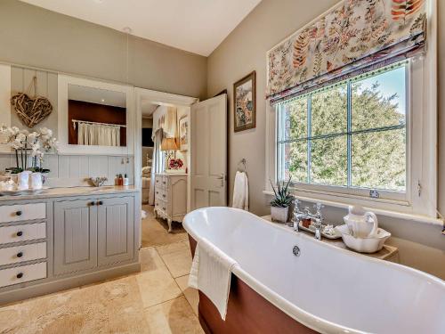 baño grande con bañera y ventana en Willington Lodge, en Hanmer