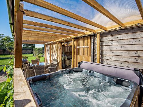 a hot tub in a backyard with a pergola at Willington Lodge in Hanmer
