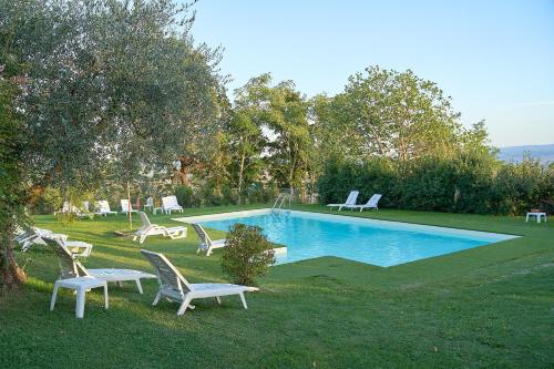 una piscina con sillas blancas en Il Poggio, en Celle sul Rigo