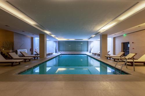 a swimming pool in a hotel with chairs and tables at Astir Odysseus Kos Resort and Spa in Tigaki
