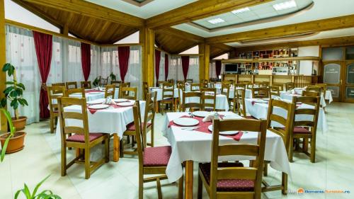 une salle à manger avec des tables blanches et des chaises en bois dans l'établissement Anomis, à Cîmpulung