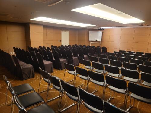 a lecture hall with chairs and a white screen at Hotel bridge Seogwipo in Seogwipo