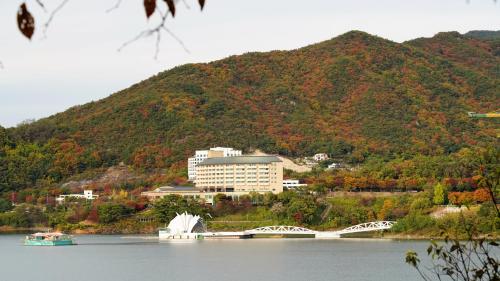 a building on the shore of a lake with a bridge at Cheongpung Resort in Jecheon