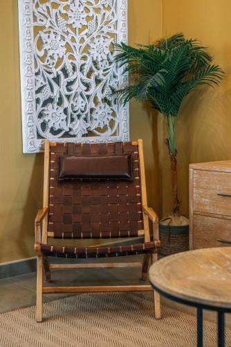 a brown chair in a room with a plant at Apartamentos Turísticos La Baílla in Rota