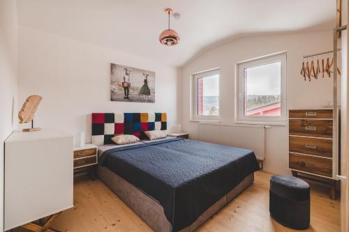 a bedroom with a bed and two windows at KORZO Lipno in Lipno nad Vltavou