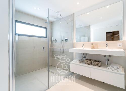 een badkamer met een douche, een wastafel en een spiegel bij HigueronRentals Malibu in Málaga