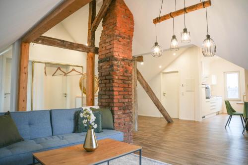 a living room with a blue couch and a brick pillar at Modernes Loft in Ramstein - mit Sauna & TLA in Ramstein-Miesenbach