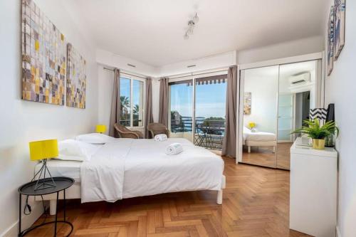 a bedroom with a large white bed and a balcony at Croisette - 2 Chambres - Vue Epoustouflante in Cannes