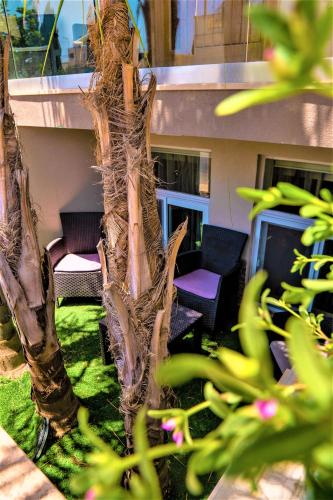 a patio with chairs and a palm tree at St. Peter's Pool Holiday Apartment in Marsaxlokk