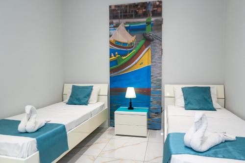 two beds in a room with a painting on the wall at St. Peter's Pool Holiday Apartment in Marsaxlokk