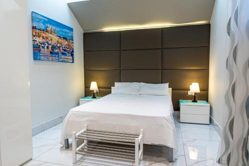 a bedroom with a large white bed and two lamps at St. Peter's Pool Holiday Apartment in Marsaxlokk