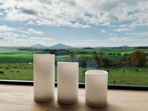 three white candles sitting on a table in front of a window at Krabička K74 in Jablonné v Podještědí