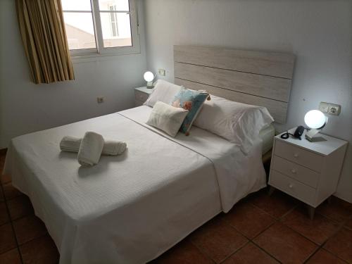 a bedroom with a white bed with two towels on it at Apartahotel Vistamar San José in San José