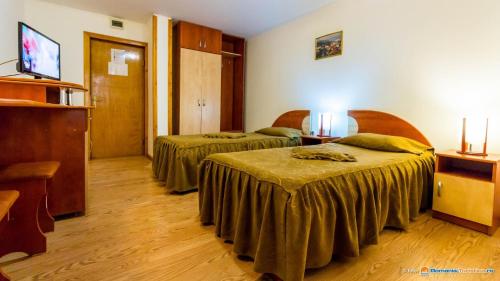 a hotel room with two beds and a flat screen tv at Anomis in Cîmpulung