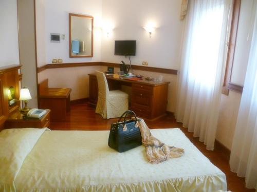 a hotel room with a bed and a desk with a bag at Hotel Minerva in Pordenone
