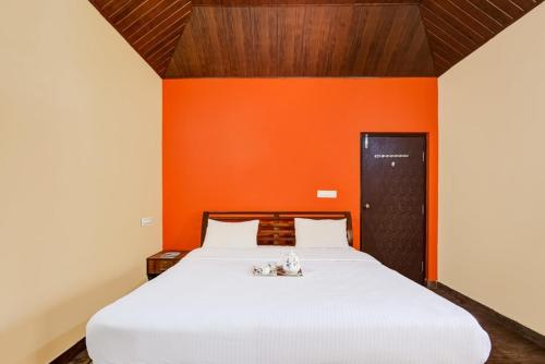 a large white bed with an orange wall at Coorg Bliss Estate Stay in Madikeri