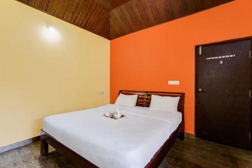 a bedroom with a large white bed with an orange wall at Coorg Bliss Estate Stay in Madikeri