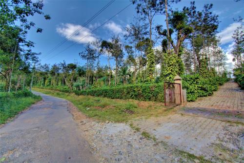 an empty road with a gate in a field at Coorg Bliss Estate Stay in Madikeri
