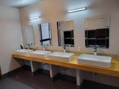 three sinks in a public bathroom with mirrors at Villa 33 Kashikojima in Ugata