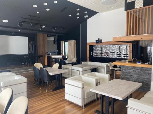 a restaurant with white tables and chairs and a bar at Villa 33 Kashikojima in Ugata