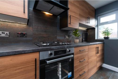 赫爾河畔京士頓的住宿－belmont street，厨房配有木制橱柜和炉灶烤箱。