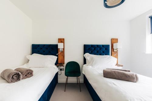 two beds in a room with a green chair at Charlecote House in Bath
