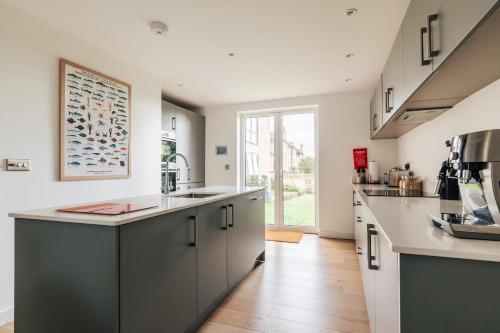 a kitchen with white cabinets and a large window at Charlecote House in Bath
