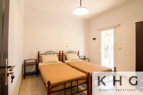 two beds in a room with a window at Irene apartment in Vlachata village! in Kefallonia