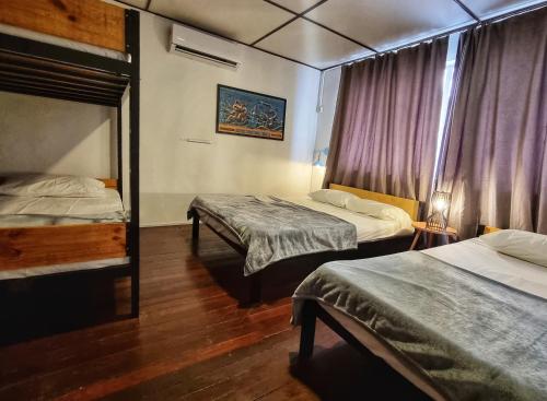 a hotel room with two beds and a window at Treehouse Hostel in Kuching
