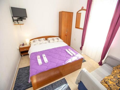 ein Schlafzimmer mit einem lila Bett und einem Sofa in der Unterkunft Apartment Brunac in Brbinj