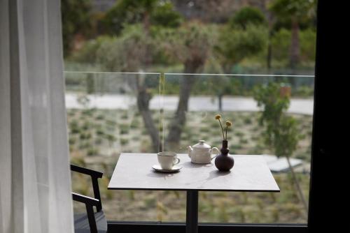 a table with a coffee cup and a vase on a window at Helea Lifestyle Beach Resort in Kallithea Rhodes