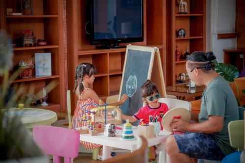 a man and two children playing with a toy at Cosy Beach Hotel - SHA Extra Plus in Pattaya South