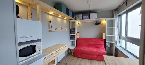 a small room with a red couch in a tiny house at Studio fonctionnel 16m2 avec vue panoramique in Puy-Saint-Vincent