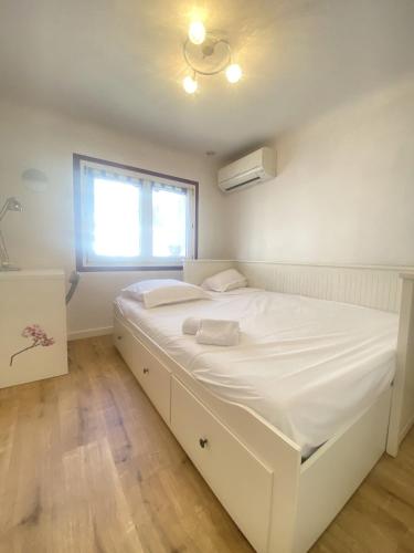 ein weißes Bett in einem Zimmer mit Fenster in der Unterkunft Maison T3 La Bayore - clim - wifi -5minutes centre ville in Hyères
