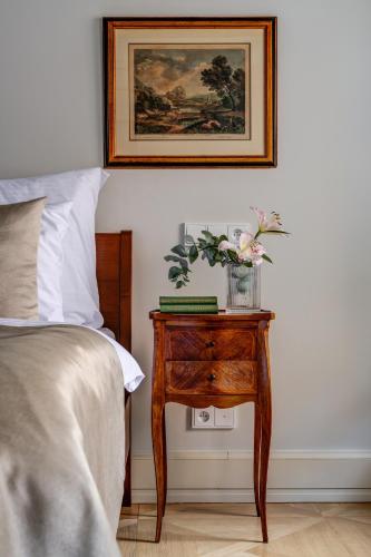 a bedroom with a nightstand with a bed and a picture at Hotel Nerudova 211 in Prague