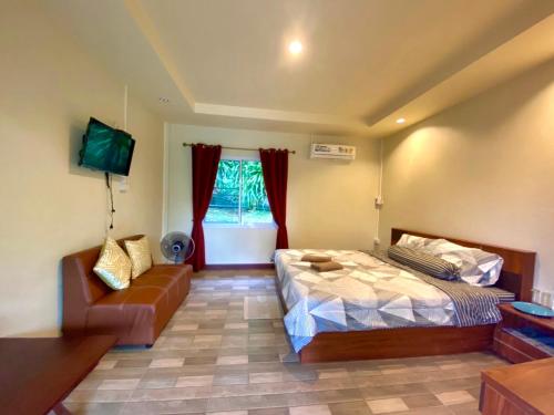 a bedroom with a bed and a couch at นพรัตน์การ์เด้นฮิลล์ in Uthai Thani
