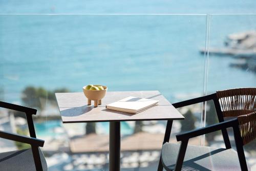 a table with a book and a bowl of fruit on it at Helea Lifestyle Beach Resort in Kallithea Rhodes