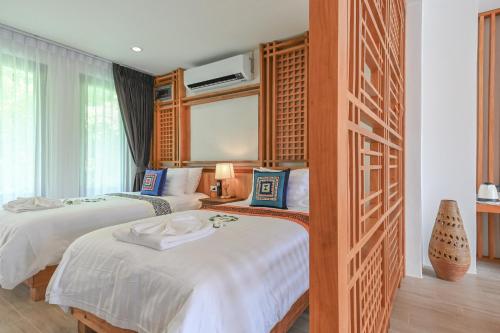 a hotel room with two beds and a tv at Cascade Tara in Na Mueang