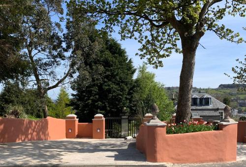 a fence with a tree and flowers in front of a house at Ivybank Villa in Rothesay