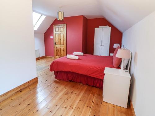 a bedroom with a red bed and a wooden floor at Fernwood in Killarney