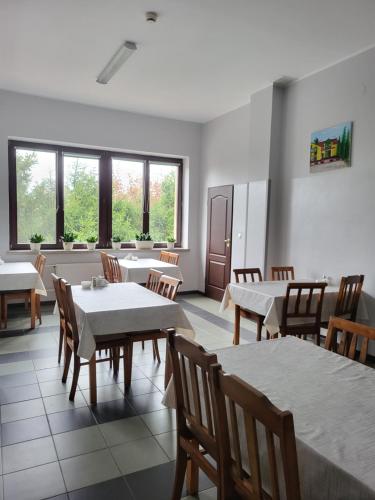 a dining room with tables and chairs and windows at Hotelik OSiR Lubawa in Lubawa